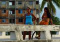 Zwei Frauen am Straßenrand in Havanna, im Hintergrund ein Haus